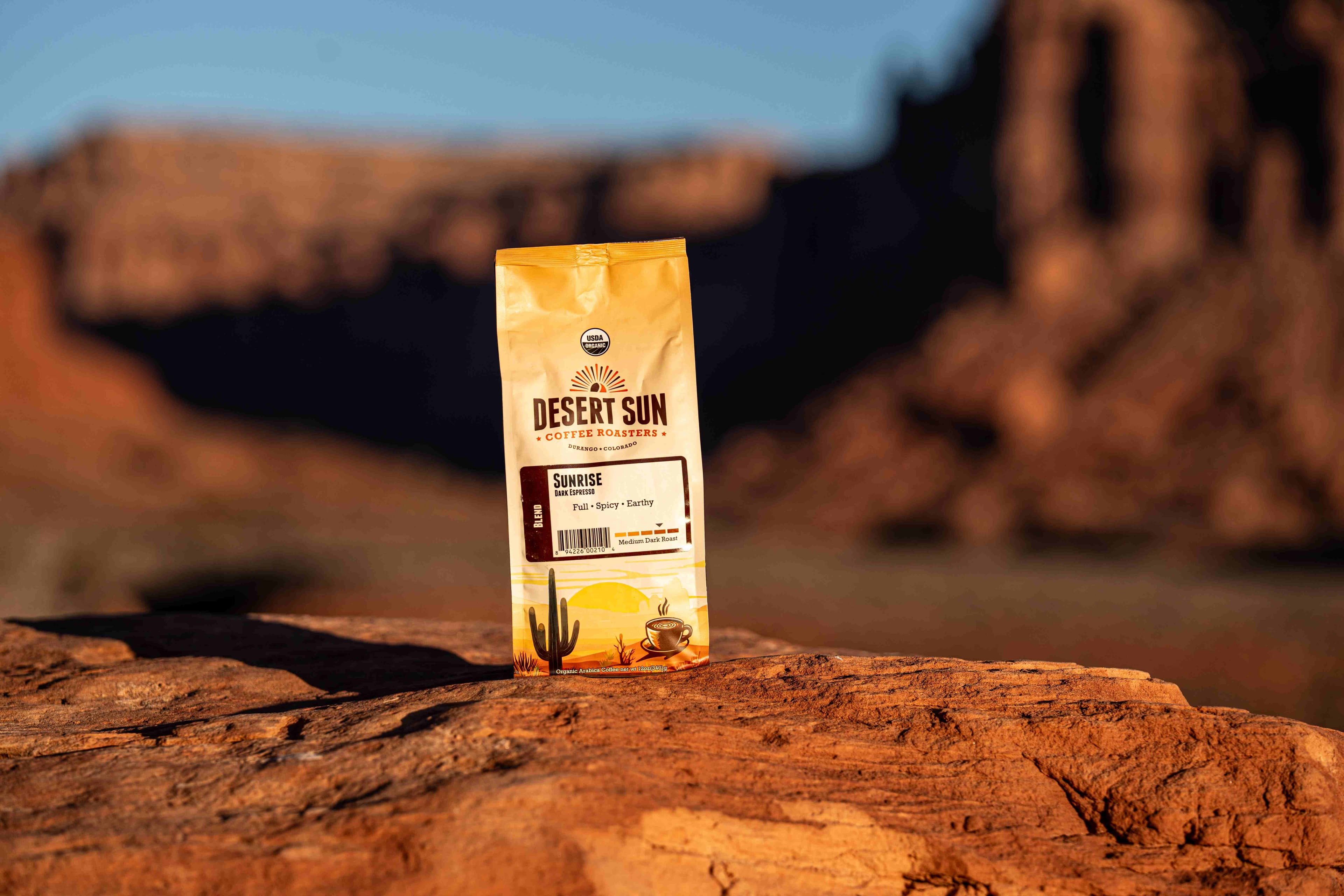 A bag of Desert Sun Sunrise espresso on a sandstone ledge in warm morning light