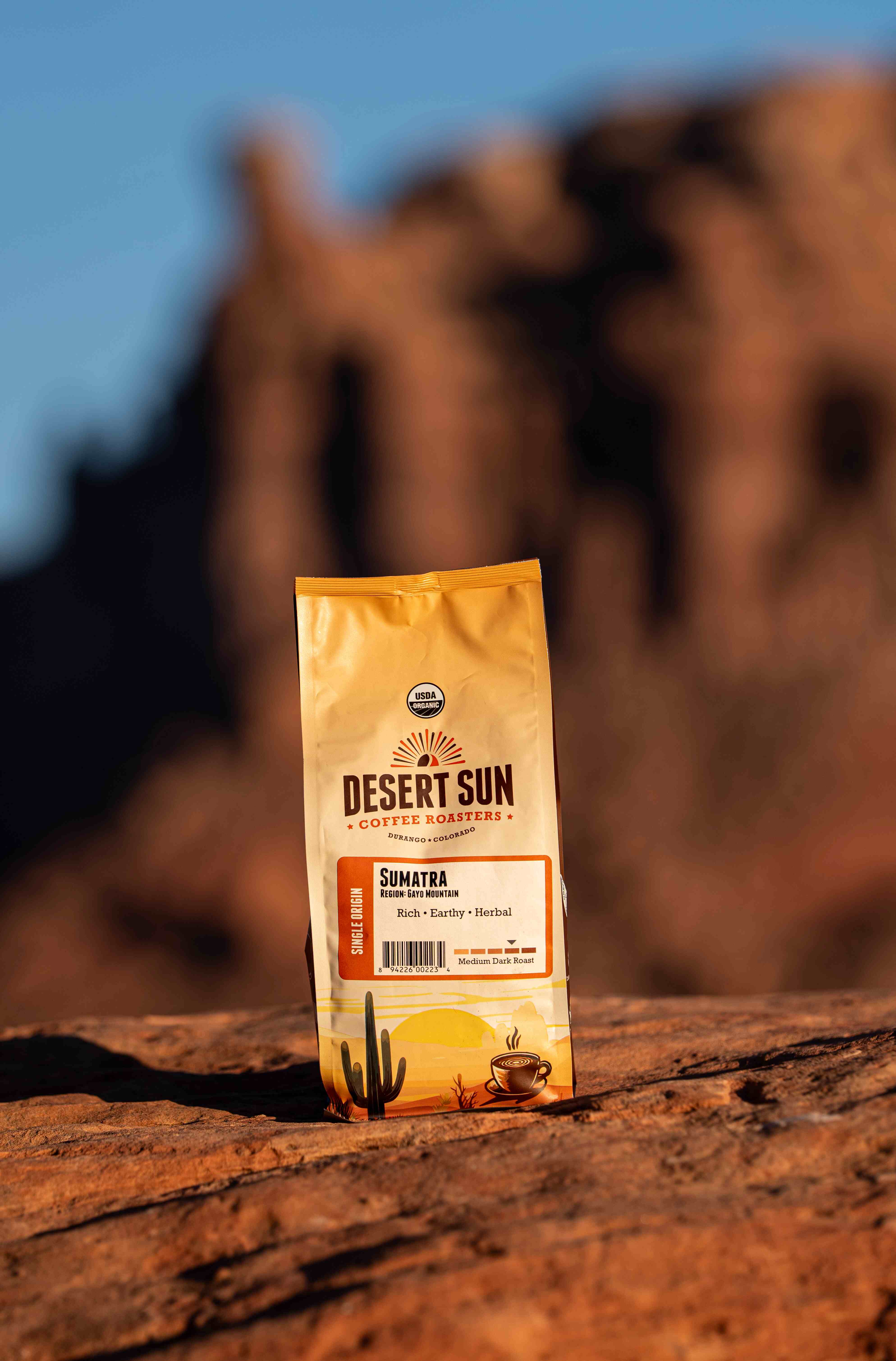 A bag of Desert Sun Sumatra on red sandstone, a sandstone spire blurred behind it