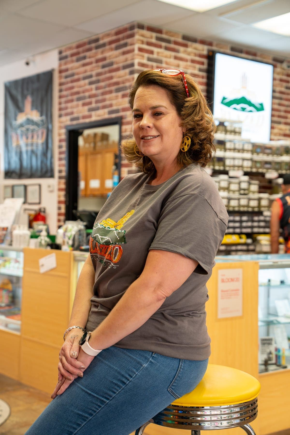 Jennifer, one of the owners, sitting on a yellow stool at the counter