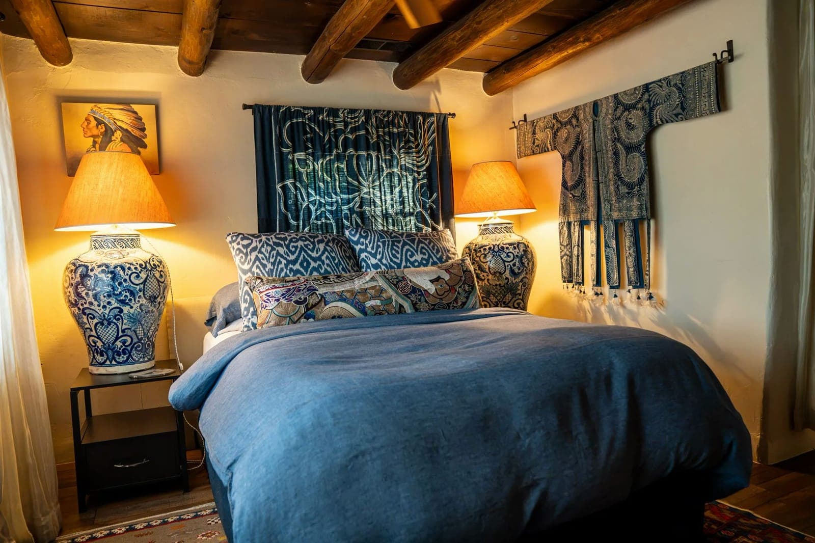 The blue bedroom at Los Santos: a deep blue duvet, ikat pillows, blue-and-white ginger-jar lamps, and textiles hung on the wall