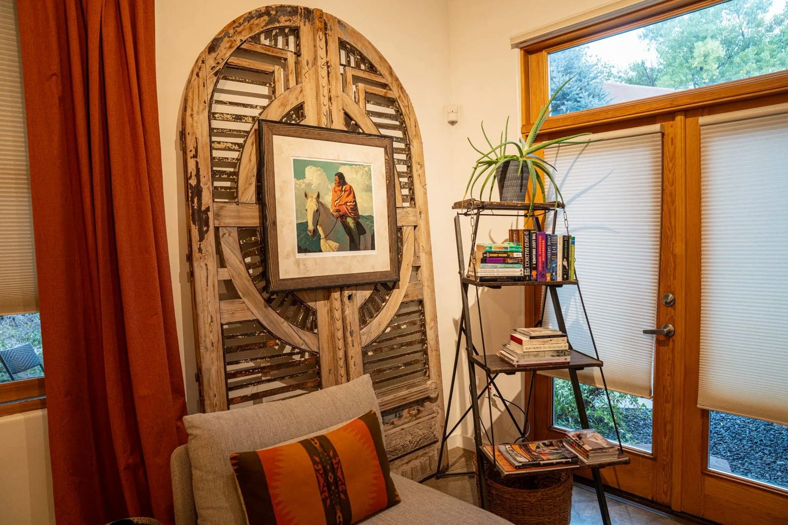 A corner of Sage, the Railyard studio: a carved wooden arch framing a painting, an orange curtain, and bookshelves by the glass doors