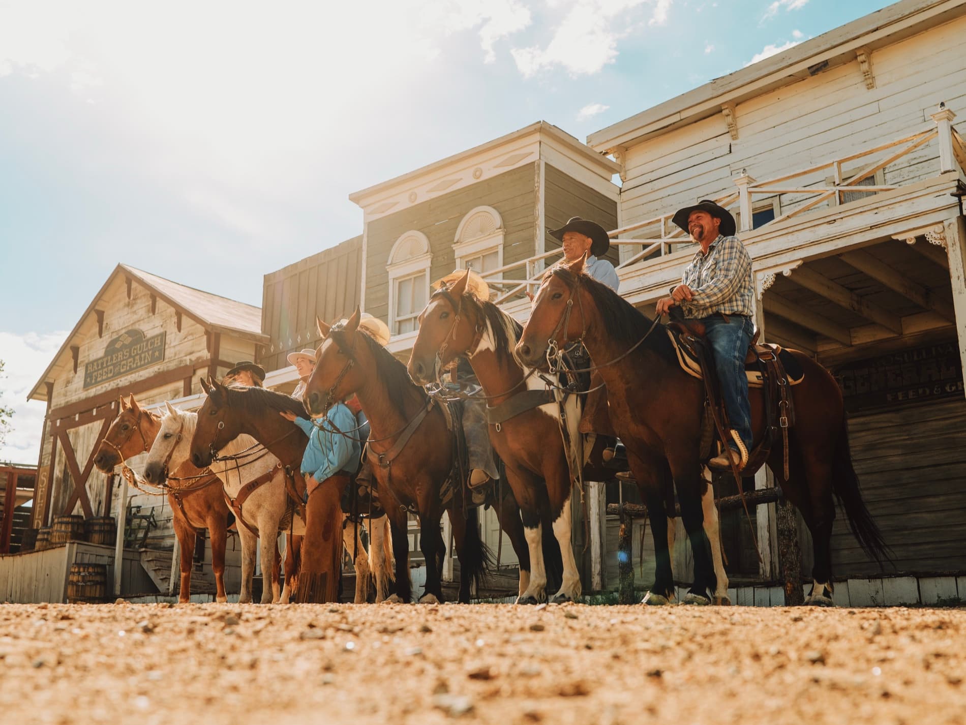 A row of riders and horses backlit by sun flare at the 6666 Ranch