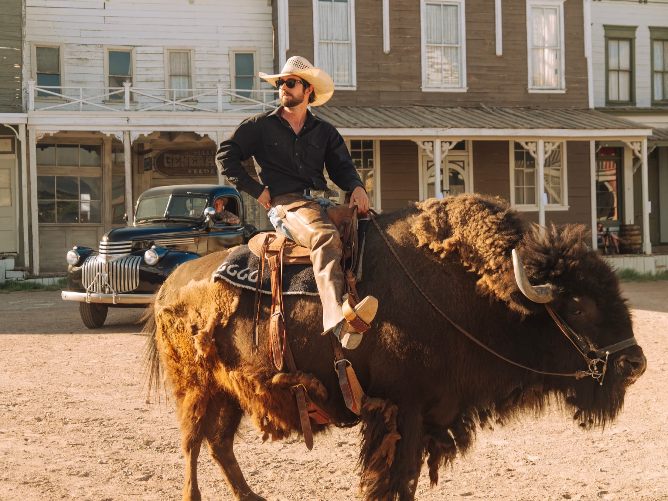 Wyatt Mortenson, the Buffalo Rider, riding Clyde the buffalo down the ranch's ghost-town street in golden light