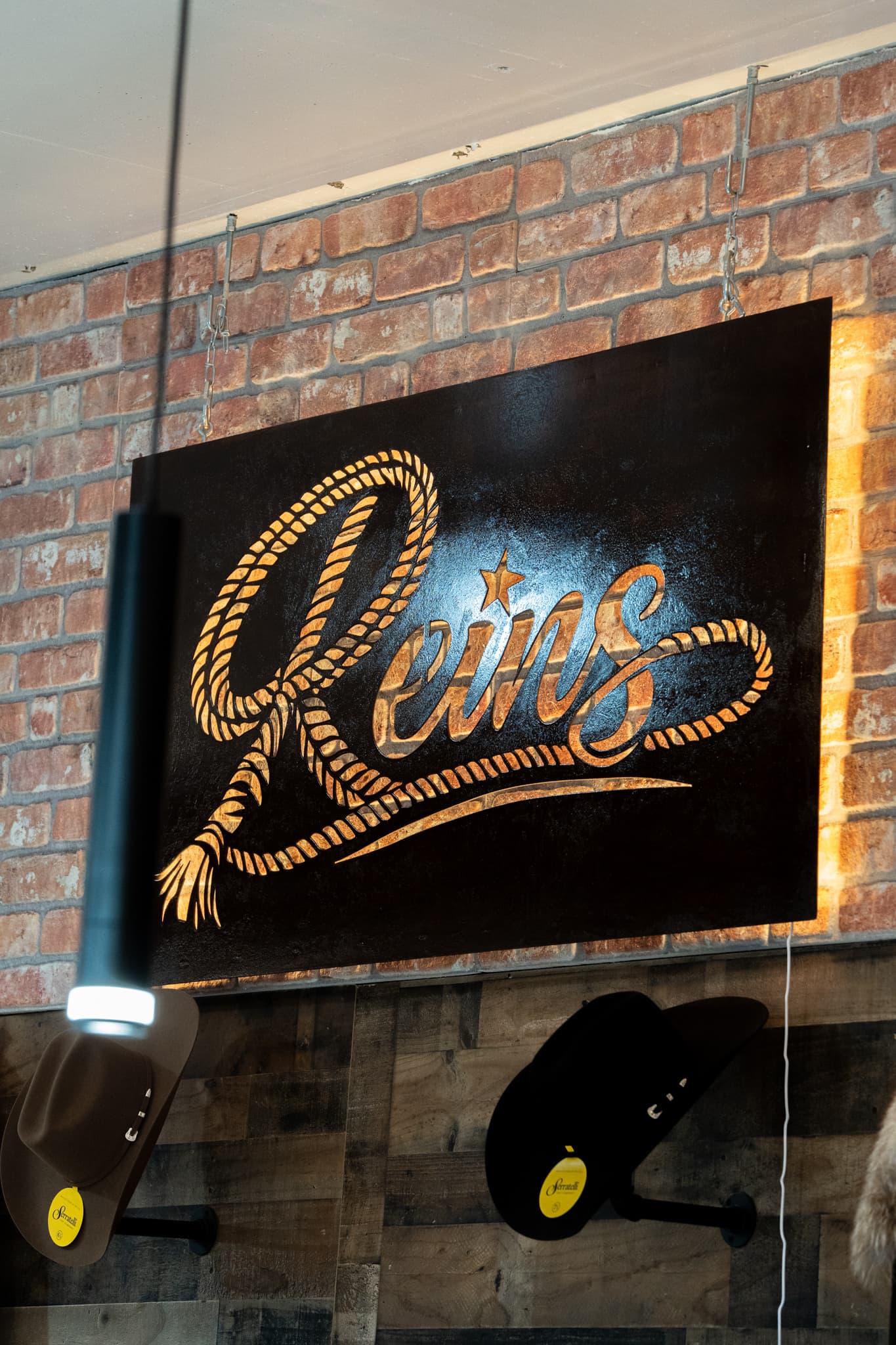 The Reins Western Goods rope-script logo, designed by Creative Flow Studio, on the shop wall