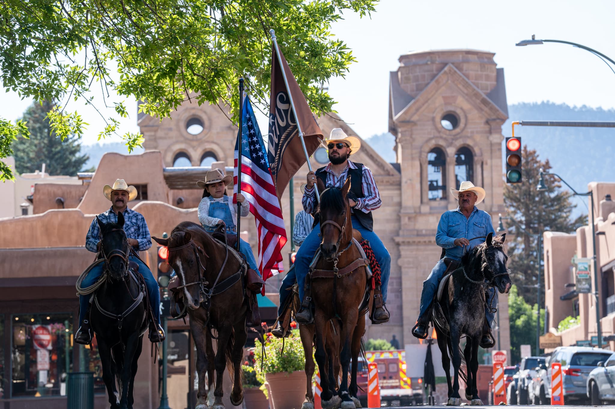 Reins Western Goods riders carrying the brand flag past the cathedral on the Santa Fe Plaza