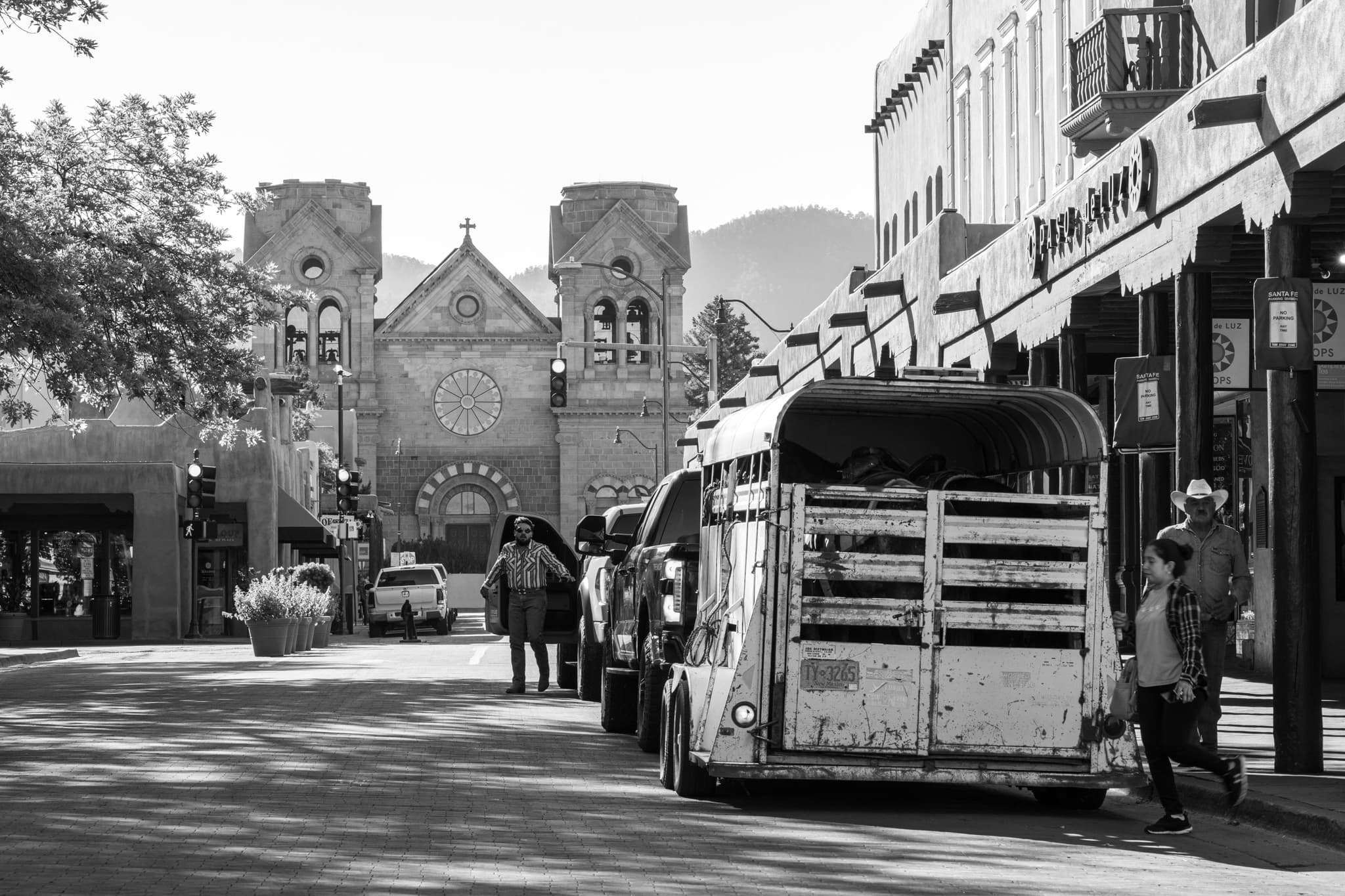 Black-and-white photo of a horse trailer parked on a downtown Santa Fe street, the cathedral at the end of the block, shot for Reins Western Goods — a Creative Flow Studio frame.