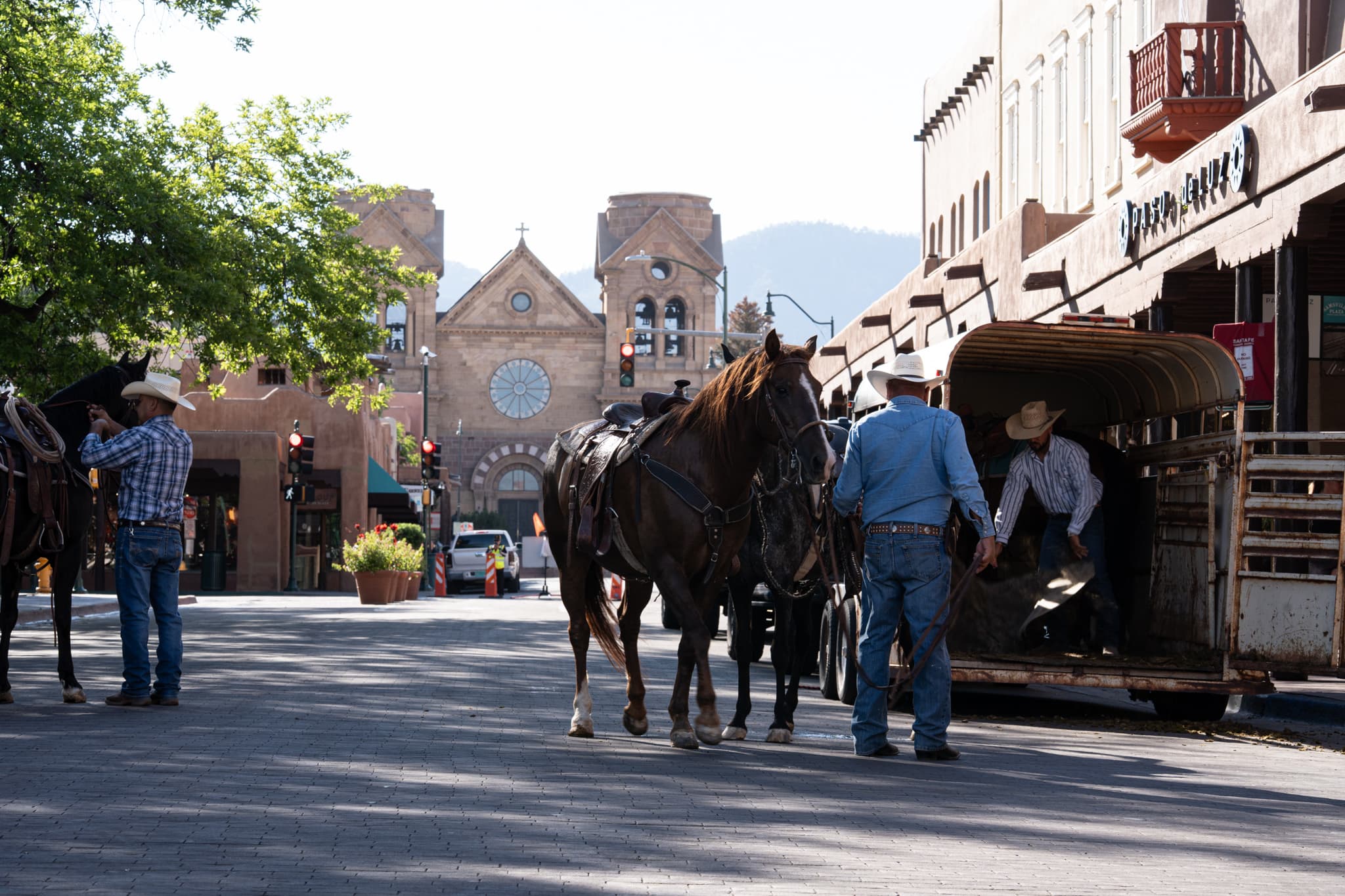 A rider leading a saddled horse off a trailer on a downtown Santa Fe street before the ride