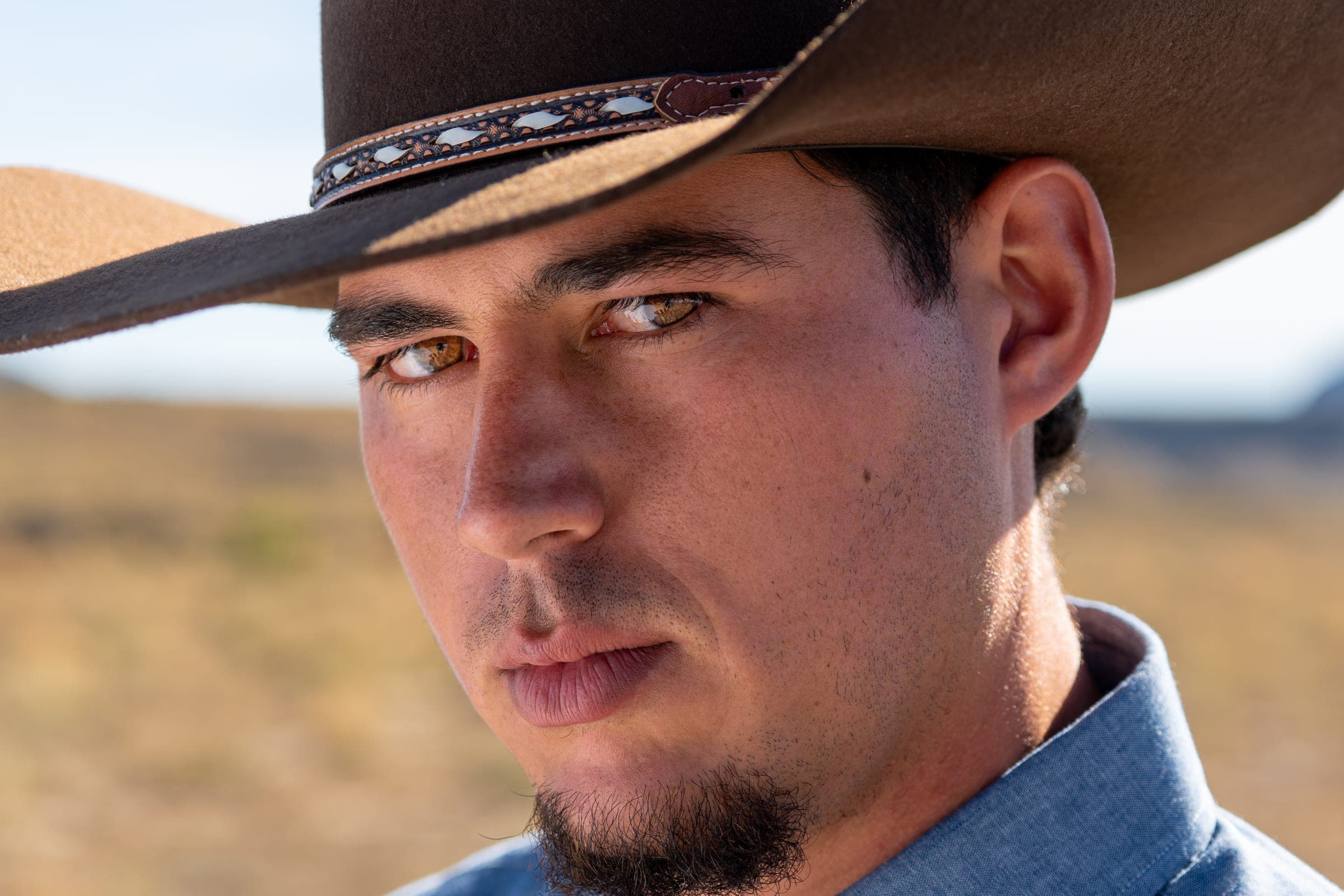 Cowboy on a white horse galloping down a dirt road as a small plane comes in low behind him